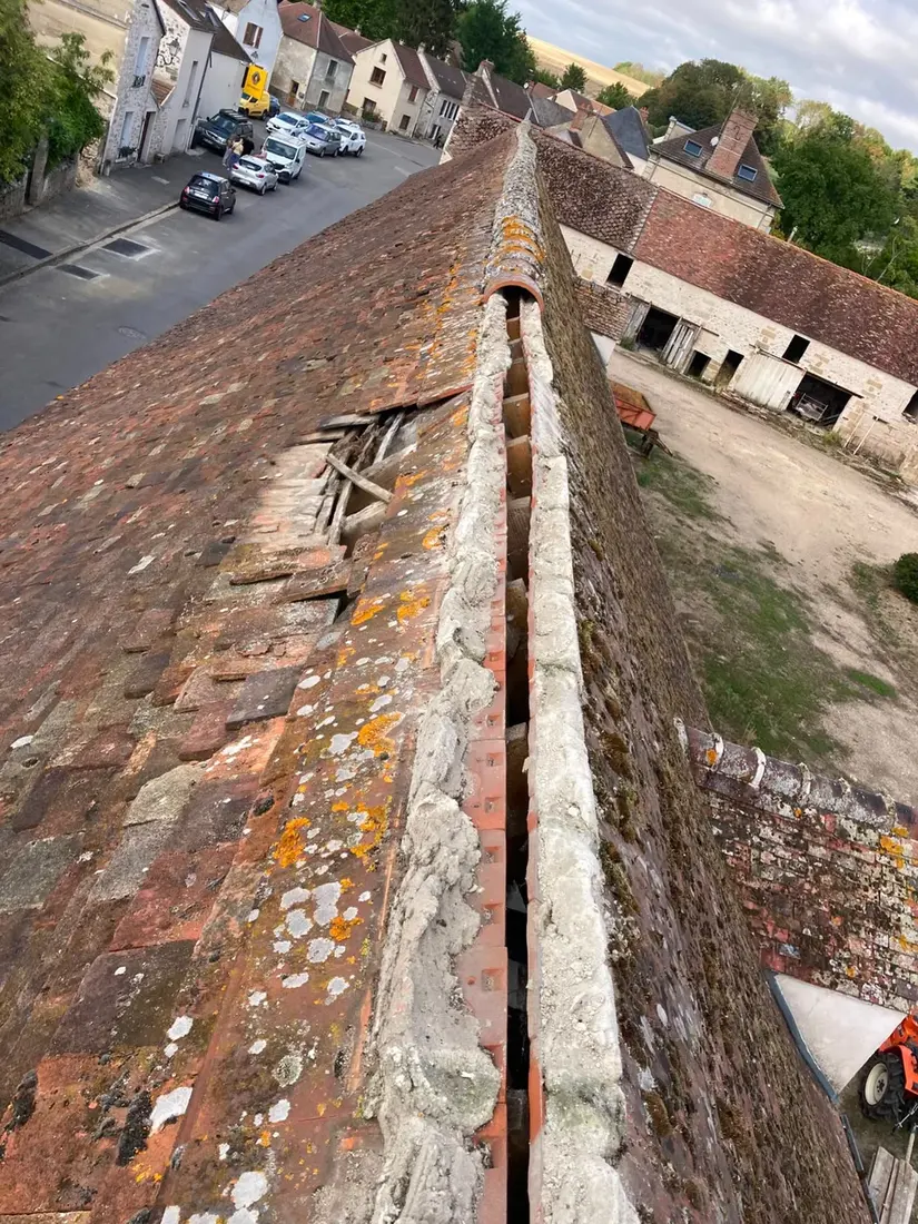 Ligne de faîtage ouverte avec mortier dégradé sur un long pan de tuiles plates