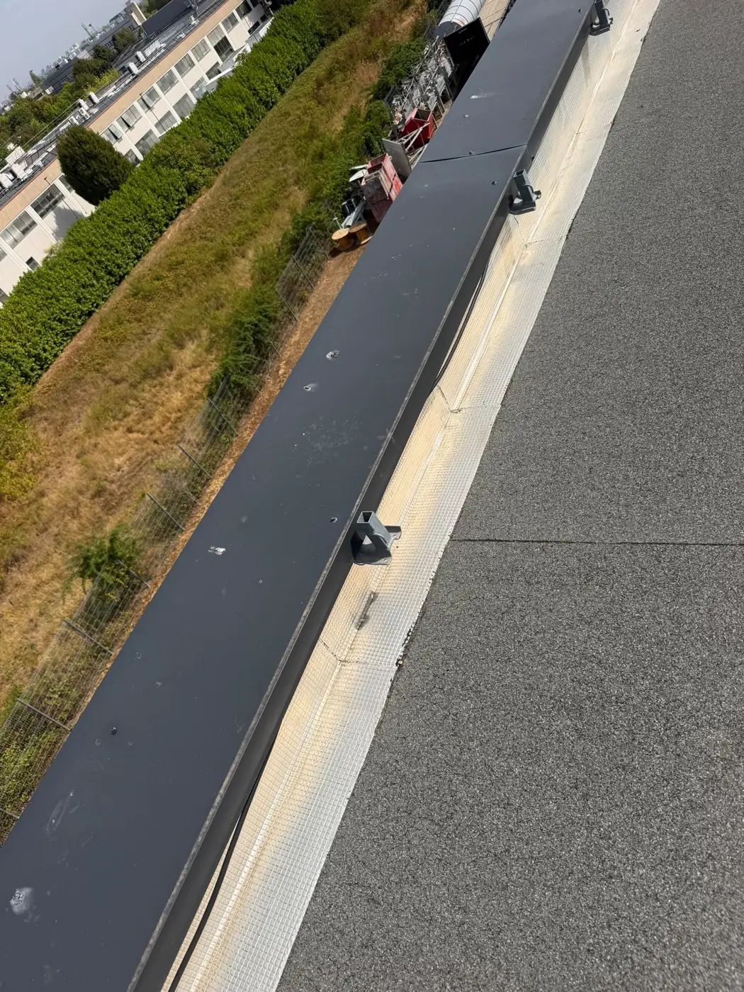Couvertine aluminium anthracite en tête d'acrotère, pattes de fixation et bande de solin sur toiture-terrasse