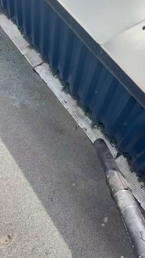 Pied d'acrotère nettoyé sur une toiture-terrasse, bande de solin et joint de tête à nouveau visibles