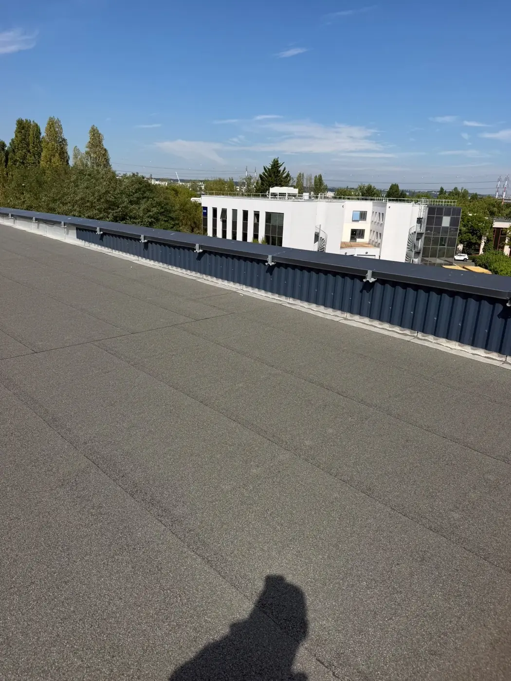 Vue d'ensemble d'une rive de toiture-terrasse : acrotère, couvertine et surface en bitume autoprotégé